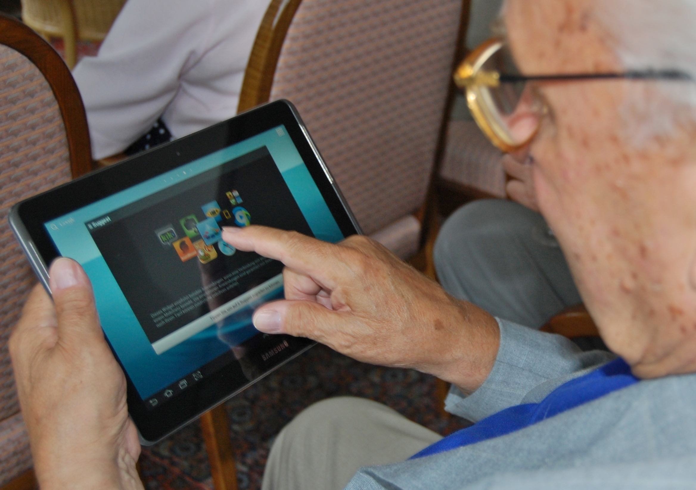 Older person using a tablet with guided support.